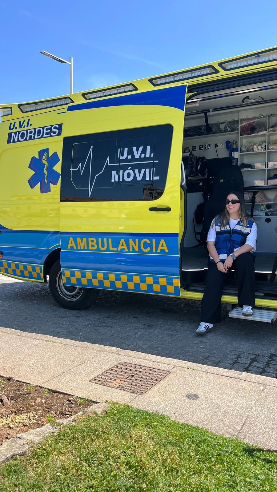 Técnica en emergencias sanitarias de Ambulancias do Nordés junto a la puerta abierta de una U.V.I. Móvil equipada