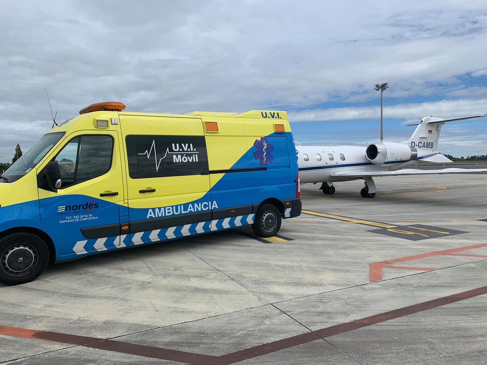 Ambulancia medicalizada U.V.I. Móvil de Ambulancias do Nordés en la plataforma del aeropuerto de Santiago, junto a un jet privado